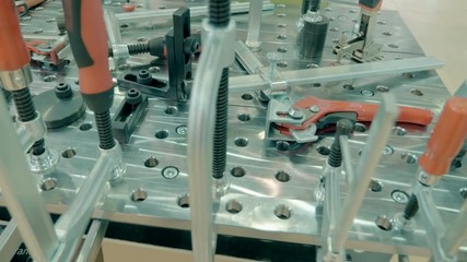 Workshop with a metal welding table and a lot of different clamps, guides and precision instruments for fixing individual parts and subsequent welding in a single frame. Shot in motion