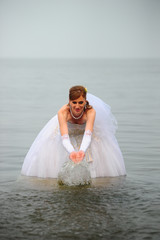 Fototapeta na wymiar Bride in a wedding dress on a wakeboard slides on the lake.