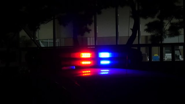 Flashing lights of the police car in front of the building window 01