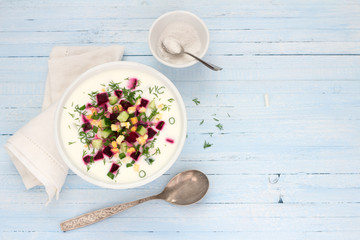 Delicious summer soup, beetroot soup (svekolnik, holodnik) on kefir, with cucumber, boiled eggs and greens. traditional Lithuanian, Russian, Ukrainian, Belorussian or Polish cuisine. on a wooden table