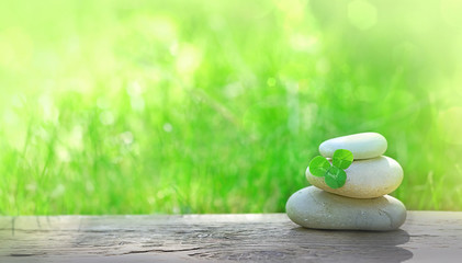 Stack of zen stones and Shamrock clover leaf on abstract nature background. Relax still life with...