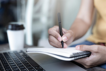 Women holding a pen writing a notebook. Recording and business concept.