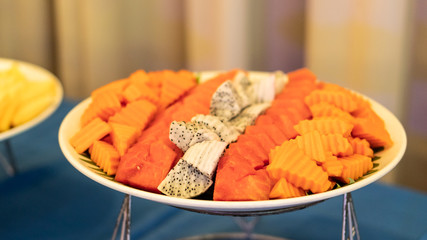 Various types of fruit with dragon fruit and papaya on the table, blurred background at parties