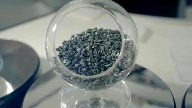 Various types of polymer pellets and powders in glass containers. Shot in motion