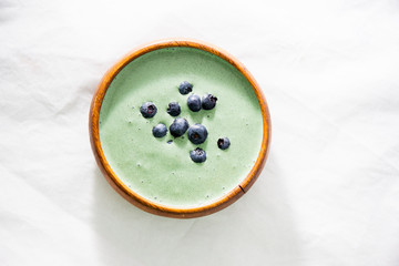 Spirulina yogurt with fruit in wooden bowl