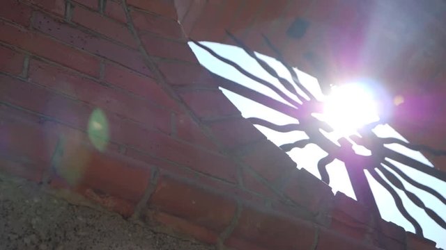 Sunlight streaming though a pagan cross located in a brick wall. SLOW MOTION