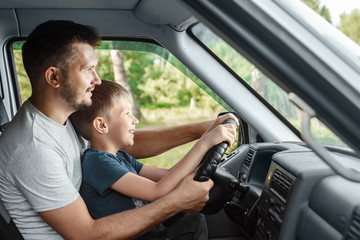 Man, father teaches little son to drive on the road. Parents and children, dad and son