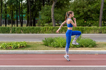 young girl warming up on a treadmill before the race. Training outdoors in good summer weather.