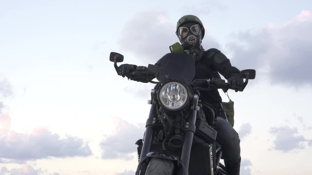 Biker woman with a pollution mask in army helmet on Motorcycle  on the old desert  road. Concept You say No War