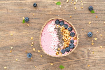 Healthy smoothie bowl with granola, coconut, chia, yogurt and fresh blueberries on wooden background. Breakfast smoothie bowl, top view.