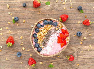 Smoothie bowl with granola, yogurt, Chia, strawberry and fresh blueberries on wooden background. Breakfast smoothie bowl, top view. 