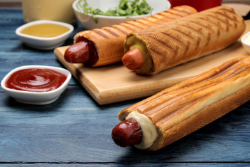 French hot dogs. Tasty hot dogs on the board and sauce on a blue wooden table. fast food street food. sausages in a bun.