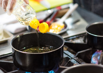 Chef pouring oil in frying pan, Chef cooking food in the kitchen