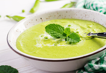 Green pea soup in bowl on wooden table. French cuisine.