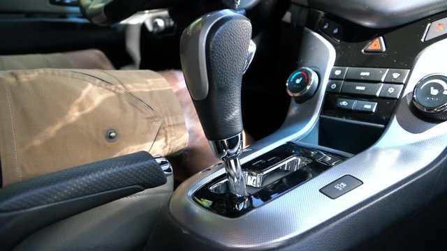 A man switches the selector of the automatic transmission in manual mode