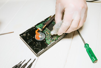 Man repairing hard disk. Inside details of the old personal computer. Broken PC. Soldering iron in...