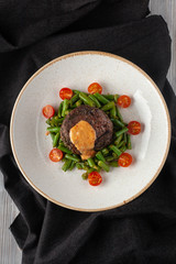 Medium rare mignon fillet roasted with green beans and fresh cherry tomatoes, decorated with creamy sauce for a healthy dinner in a restaurant