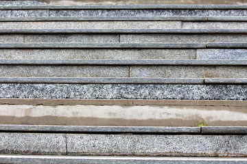 Grey marble tiles staircase texture with fallen cracked tiles and visible concrete foundation on rainy spring day