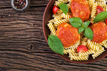 Fusilli  pasta with meatballs in tomato sauce and basil in bowl. Italian cuisine. Top view. Flat lay