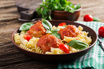 Fusilli  pasta with meatballs in tomato sauce and basil in bowl. Italian cuisine.