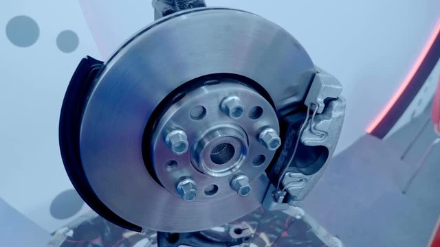New caliper with brake pads and brake disc are shiny in the light is presented for review at the exhibition. Shot in motion