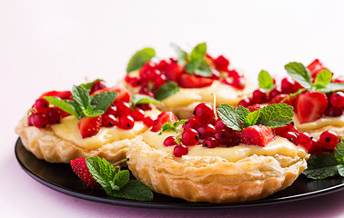 Tarts with strawberries, currant and whipped cream decorated with mint leaves.