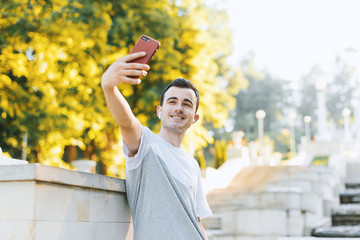 Cheerful young man si taking a selfie smiling in the park.