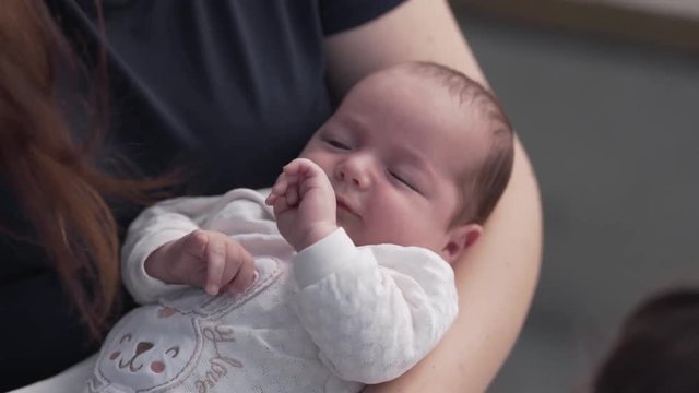 Young beautiful mother is holding her lovely baby on a hands and kissing him.