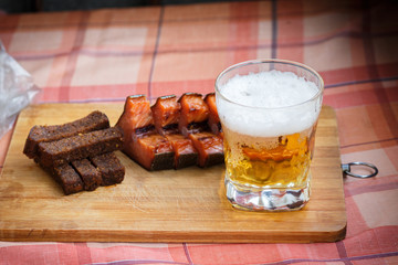A glass of light beer with smoked fish and black fried bread in garlic. Beer and beer snack on a wooden Board.