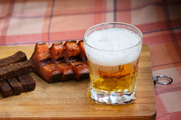 A glass of light beer with smoked fish and black fried bread in garlic. Beer and beer snack on a wooden Board.