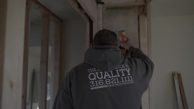A man works inside remodeling a house - uses foam insulation.