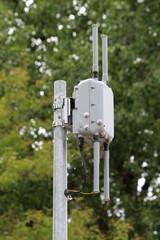 Outdoor Wi-Fi access point with four antennas mounted on strong metal pole partially covered with...