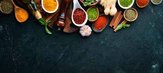 Poster Kleurrijke kruiden en specerijen om te koken. Indiase kruiden. Op een zwarte steenachtergrond. Bovenaanzicht. © Yaruniv-Studio