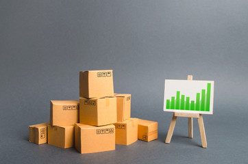 Pile of cardboard boxes and a stand with information chart. rate growth of production of goods and products, increasing economic indicators. Increasing consumer demand, exports or imports.