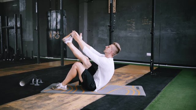 Man in good fit does abs exercises or curl up for improving sports training, single-leg toe touches, best exercises for office workers. Intermediate no equipment exersize to endurance for abs and core