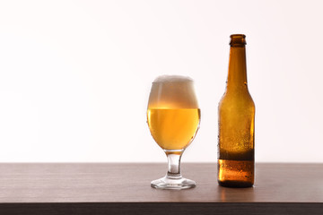 Beer bottle and glass cup on table isolated white