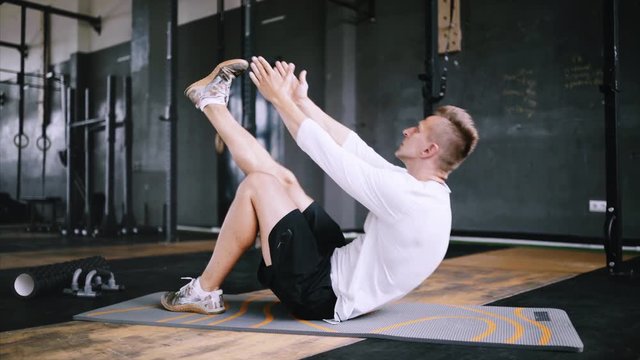 Man in good fit does abs exercises or curl up for improving sports training, single-leg toe touches, best exercises for office workers. Intermediate no equipment exersize to endurance for abs and core