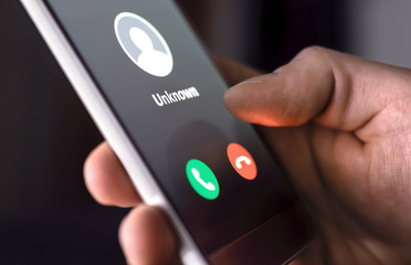 Phone call from unknown number late at night. Scam, fraud or phishing with smartphone concept. Prank caller, scammer or stranger. Man answering to incoming call. Hoax person with fake identity. - obrazy, fototapety, plakaty