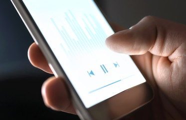 Listening to podcast, music or audiobook with mobile phone. Man using streaming service and...