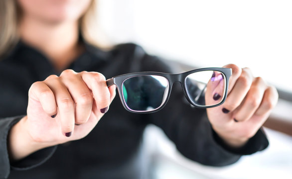 Woman holding new glasses. Lenses and spectacles getting fix and repair by professional optician. Optometrist, oculist or eye doctor in clinic. Bifocal or multifocal specs. Optometry, sight and vision