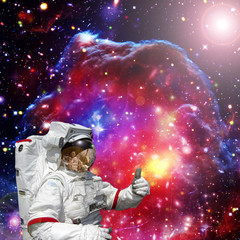 Fototapeta na wymiar Astronaut gives thumbs-up against outer space, galaxies and stars. The elements of this image furnished by NASA.
