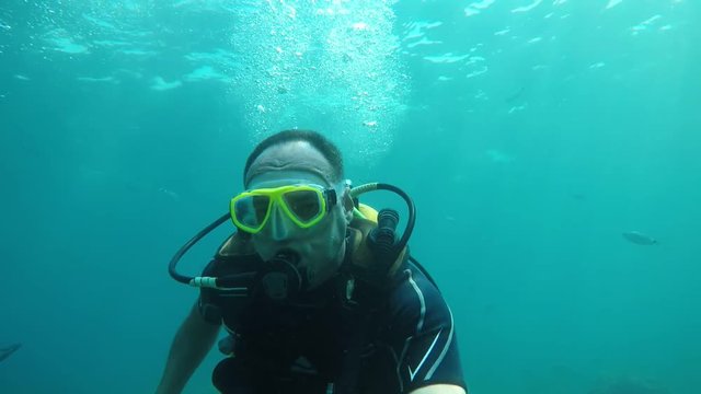 Brave man in a diving suit goes scuba diving in turquoise waters in slo-mo 