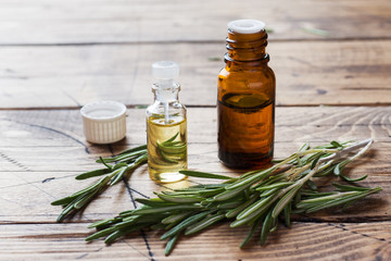 Rosemary essential oil in a glass bottle with fresh branch rosemary herb on wooden table for spa,aromatherapy and bodycare.Copy space.