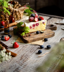 Homemade delicious slice of raspberry biscuit cake with white cream, strawberries, blueberries