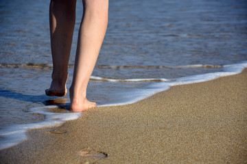 Woman legs on sandy beach. Girl walking on sand by the sea. Beach travel - Summer vacations concepts