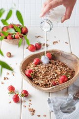 Falling milk in a bowl with granola and berries