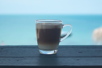 Hot coffee on a wooden table, sea view.
