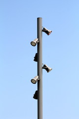 Tall strong metal pole with multiple light reflectors mounted on all sides on clear blue sky...