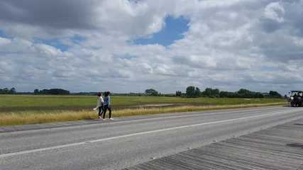 panorama avec prés salés, ciel nuageux et route avec deux voyageurs © soll