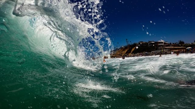 epic animated photo of the barrel of a wave on moonlight beach, taken by a GoPro in Southern California. swimmers and tourists in background.